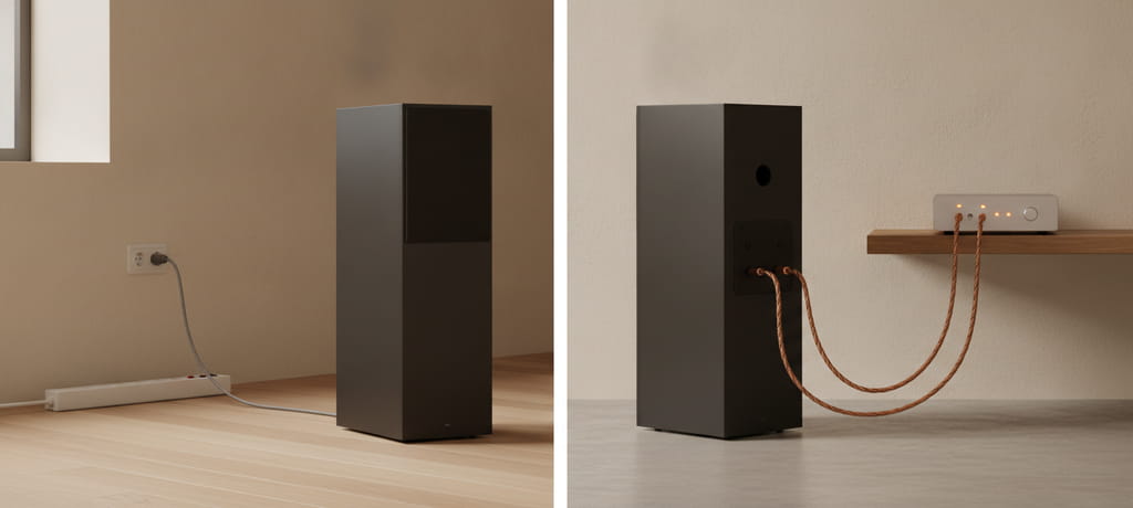 A minimalist comparison scene showing two speaker enclosures side by side in a softly lit studio room, one connected with a simple cable to a wall outlet and the other connected with thick wires to a separate amplifier unit on a shelf, warm neutral tones, clean and technical yet calm mood, no text, no logos